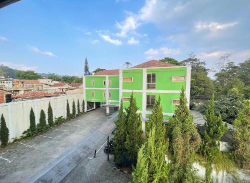 a green and white building with trees in front of it at Hotel Cemara Hijau in Bandung