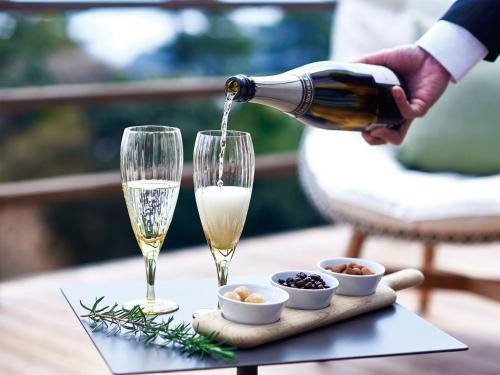 a man pouring champagne into two glasses on a table at Glamdy style hotel suite 川ノ音 in Kyū-karuisawa