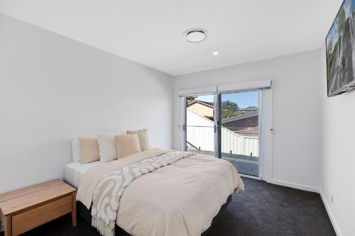 Un dormitorio blanco con una cama y una ventana. en Lakeside Retreat, en Long Jetty