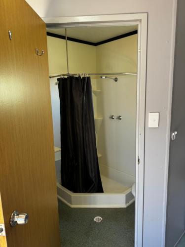 a shower with a black shower curtain in a bathroom at Summer Port Lodge in Port Hedland