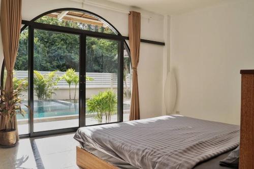 a bedroom with a bed and a large window at Secret Villa Koh Phangan in Koh Phangan