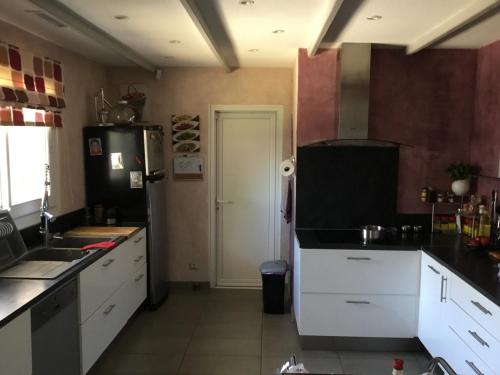 une cuisine avec des armoires blanches et un réfrigérateur noir dans l'établissement Villa paisible, à Canohès