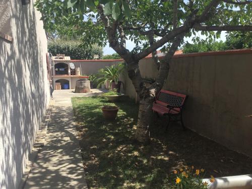 un banc rouge assis sous un arbre à côté d'un mur dans l'établissement Villa paisible, à Canohès