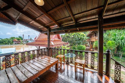 a balcony with a bench and a table and chairs at Athithara Homestay in Phra Nakhon Si Ayutthaya