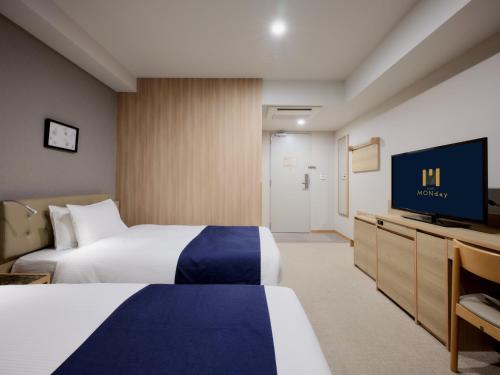 a hotel room with two beds and a flat screen tv at hotel MONday Haneda Airport in Tokyo