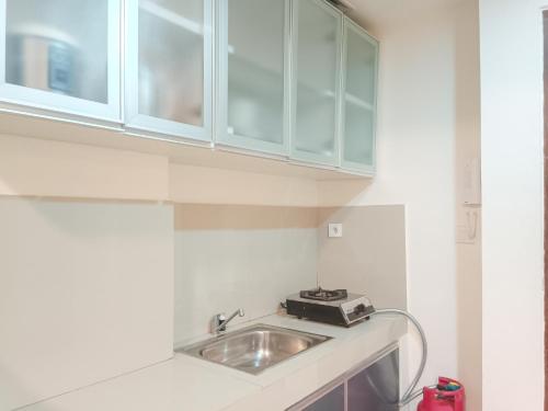 a kitchen counter with a sink and cabinets at Comfortable and Tidy 2BR at Vida View Apartment By Travelio in Pampang