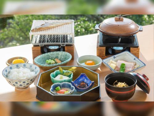 a table topped with bowls of food next to a grill at 河内長野荘 in Nagano