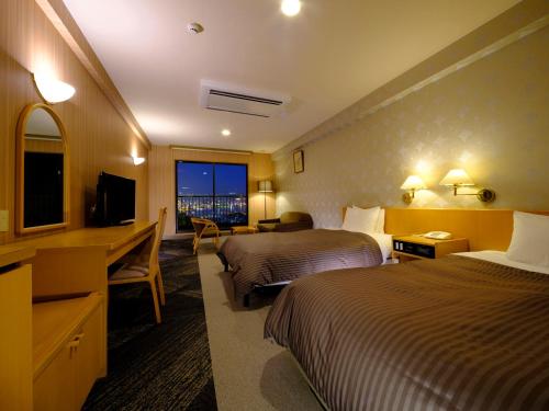 a hotel room with two beds and a desk and a television at Inasayama Kanko Hotel in Nagasaki