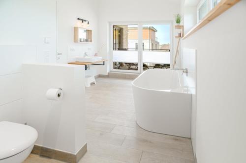 a white bathroom with a tub and a toilet at Reihe 7 in Kappeln