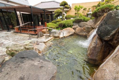 a pond with a waterfall and rocks in a yard at Nara Plaza Hotel in Tenri