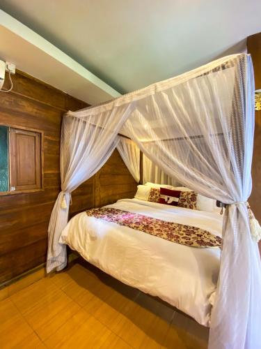 a bedroom with a bed with a canopy at Joglo Breeze Guesthouse and Villa in Tabanan