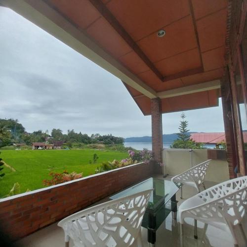 a balcony with two chairs and a view of a field at Donny Guesthouse in Tuk Tuk