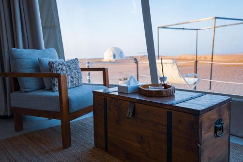 una camera con una sedia, un tavolo e una finestra di Starry Domes Desert Camp a Badīyah
