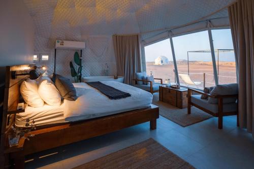 a bedroom with a bed in a room with a window at Starry Domes Desert Camp in Badīyah
