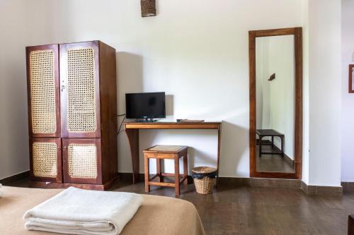 a room with a bed and a desk with a mirror at Bay Vista in Arugam Bay