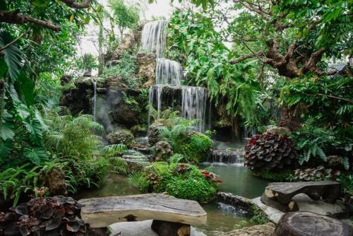 a waterfall in a garden with a bench at Natural Place in Ban Khan Ham