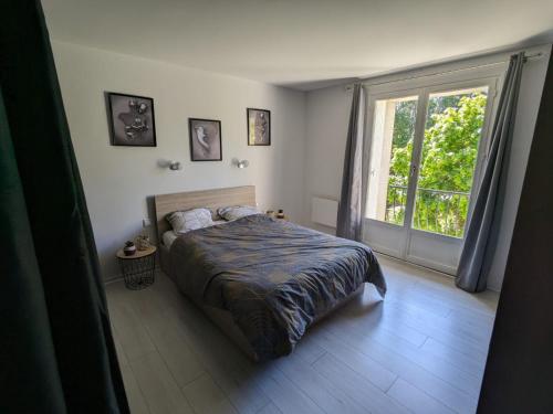 une chambre avec un lit et une grande fenêtre dans l'établissement Maison Les Hirondelles, à Carcassonne