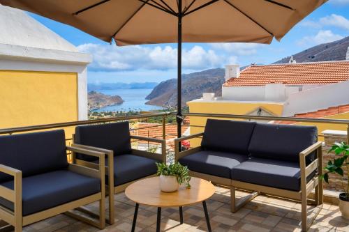 un patio avec deux chaises et un parasol dans l'établissement Village View Symi, à Symi