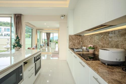 a kitchen with white cabinets and a large appliance on the counter at Luxurious 4-Bedroom Pool Villa Best Mountain Views in Hua Hin