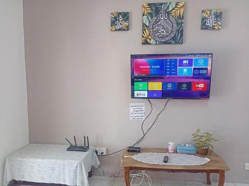 a room with a table and a tv on a wall at Homestay Atikah Bahau in Bahau