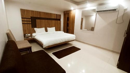 a bedroom with a bed and a chair and a mirror at HOTEL CROWN PALACE Bihar in Patna