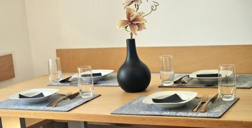 a wooden table with plates and a vase on it at Residence Moai - Exklusiver Rückzugsort für Geschäftsreisen - kostenloser Parkplatz, WLAN, Waschtrockner, Smart TV, Qbo ESSENTIAL, ergonomischer Schreibtisch in Erlangen