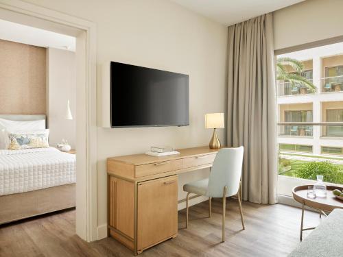 a hotel room with a desk with a tv and a bed at MarBella, Mar-Bella Collection in Agios Ioannis Peristeron
