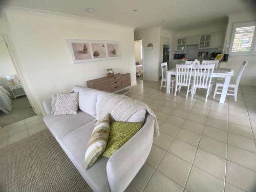 a living room with a couch and a dining room at Bungalow by the River in Shoalhaven Heads