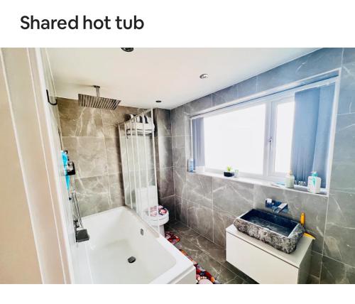 a bathroom with a white tub and a sink at Luxury room near train station and city centre in Stivichall