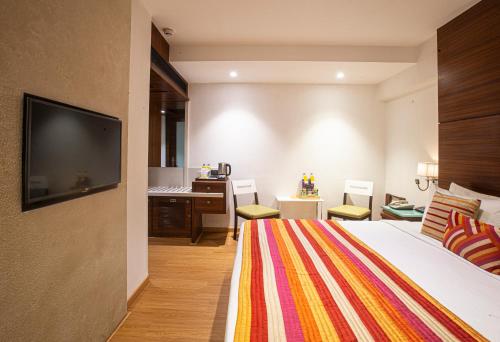 um quarto com uma cama, uma televisão e uma secretária em Hotel Bawa Continental em Mumbai