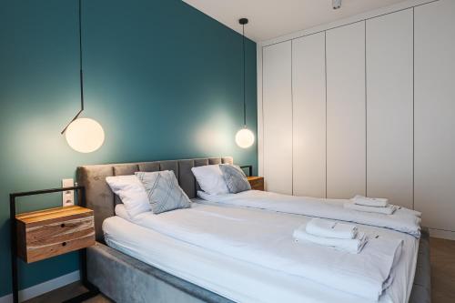 Dos camas en una habitación con paredes azules y dos luces. en Zielony Jadeit - Ucieczka od Zgiełku - Pogorzelica, en Pogorzelica