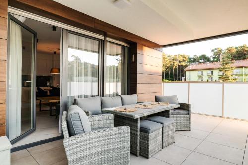 Un patio con una mesa y sillas en un balcón. en Zielony Jadeit - Ucieczka od Zgiełku - Pogorzelica, en Pogorzelica