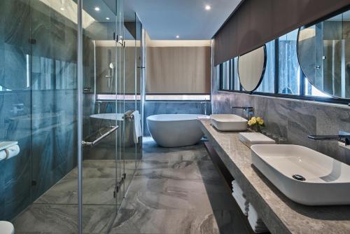 a bathroom with two sinks and a glass shower at Harbour 10 Hotel in Kaohsiung