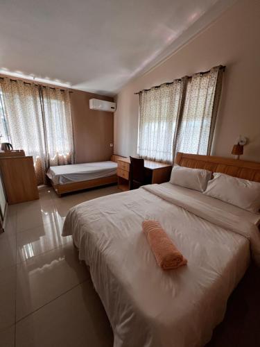 a bedroom with a large white bed and windows at Vintage Lodge in Quatre Bornes
