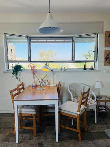 a dining room with a table and chairs and windows at Nof Beresheet in Midreshet Ben Gurion
