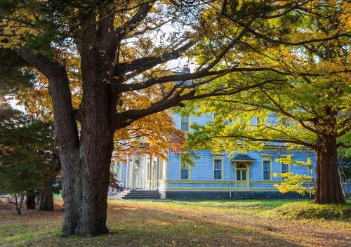 a blue house with trees in front of it at Tasogare Apartment 201 in Hakodate