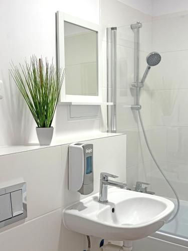a white bathroom with a sink and a shower at YiPY Apartments - Halle in Halle an der Saale