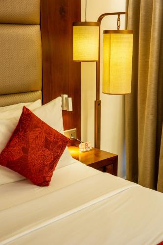 a bedroom with a bed with a red pillow and two lamps at Pegasus Reef - A Beach Resort in Colombo in Colombo