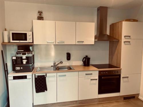 a small kitchen with white cabinets and a sink at La Bel échappée in Aubel