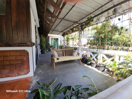 a porch with a bench in a building with plants at Kairali Palace Home Stay in Thekkady