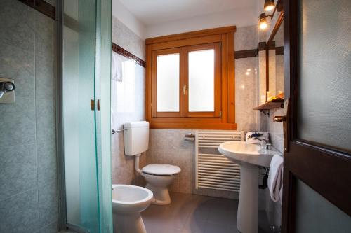 a bathroom with a toilet and a sink and a window at Hotel Olimpic in Sestriere