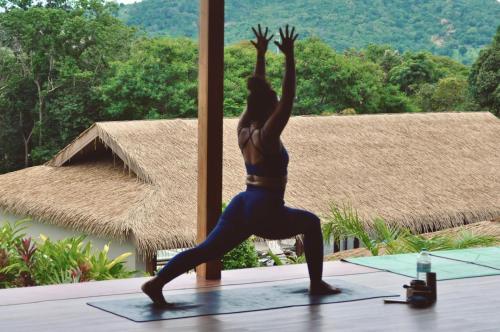 a woman doing a yoga pose in front of a window at Wild Cottages Elephant Sanctuary Resort in Amphoe Koh Samui