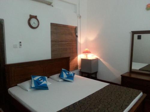 a bedroom with a bed and a mirror and a clock at Ahangama Eco Villa in Ahangama