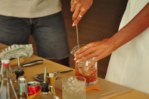 a woman is making a drink on a table at Wild Cottages Elephant Sanctuary Resort in Amphoe Koh Samui