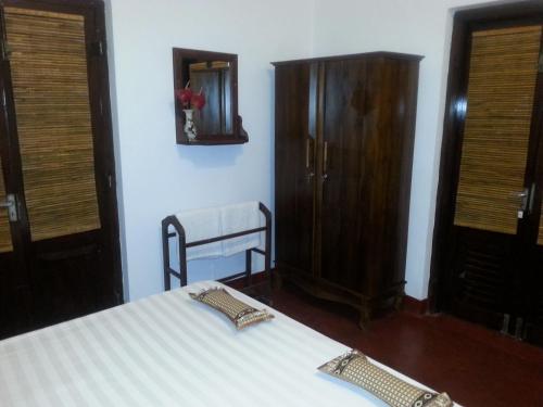 a bedroom with a bed and a wooden cabinet at Ahangama Eco Villa in Ahangama