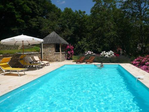 - une piscine bleue avec des chaises et un parasol dans l'établissement Le clos de fougères Les Fleuriéres, à Montoillot