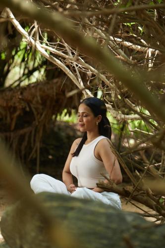 a pregnant woman sitting in meditation under a tree at Pegasus Reef - A Beach Resort in Colombo in Colombo