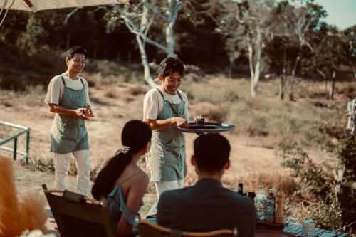 a man holding a tray with a cake on a plate at Wild Cottages Elephant Sanctuary Resort in Amphoe Koh Samui