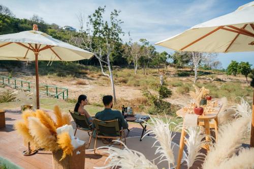 a man and woman sitting at a table under an umbrella at Wild Cottages Elephant Sanctuary Resort in Amphoe Koh Samui