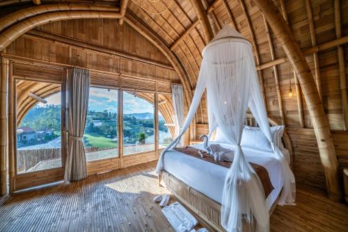a bedroom with a bed in a room with a window at The Dewi Eco Bamboo Villa in Kubupenlokan